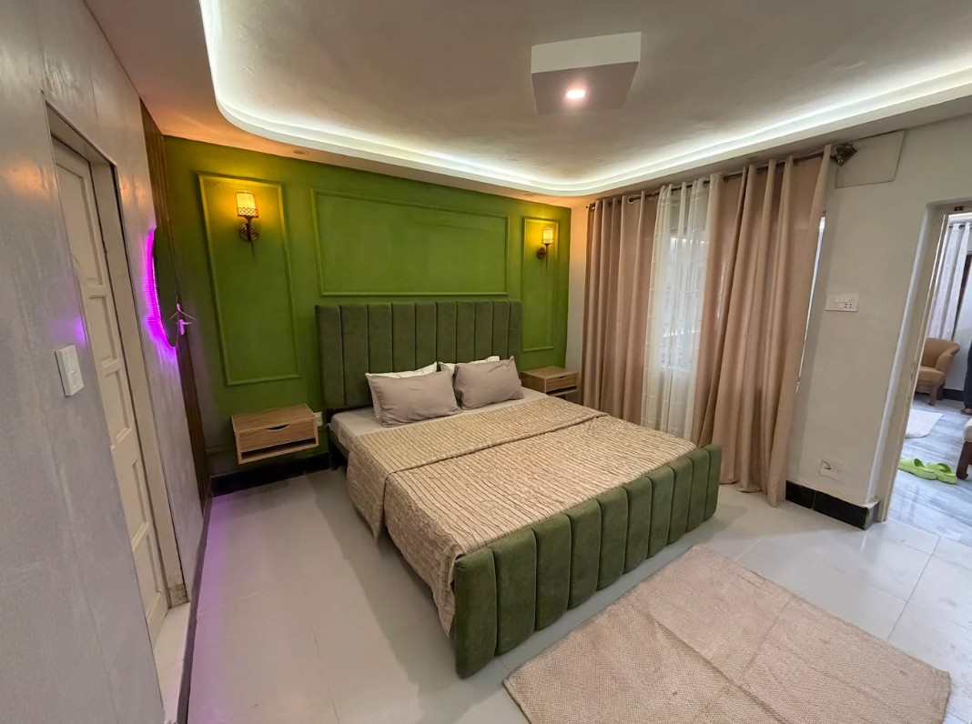 Emerald Room — bedroom with a green feature wall and tufted headboard